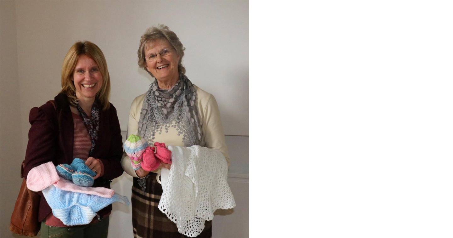 Jill Hamilton receives some of the handknit items for Baby Basics from Paddi Totten of Glenavy Open Door Club.