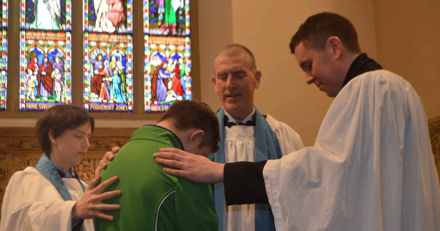 Diocesan readers Claire Henderson and Paddy Quinn, and Drumragh with Mountfield curate, the Rev Sean Hanily, pray for Team Ireland Special Olympian Lee Mitchell.