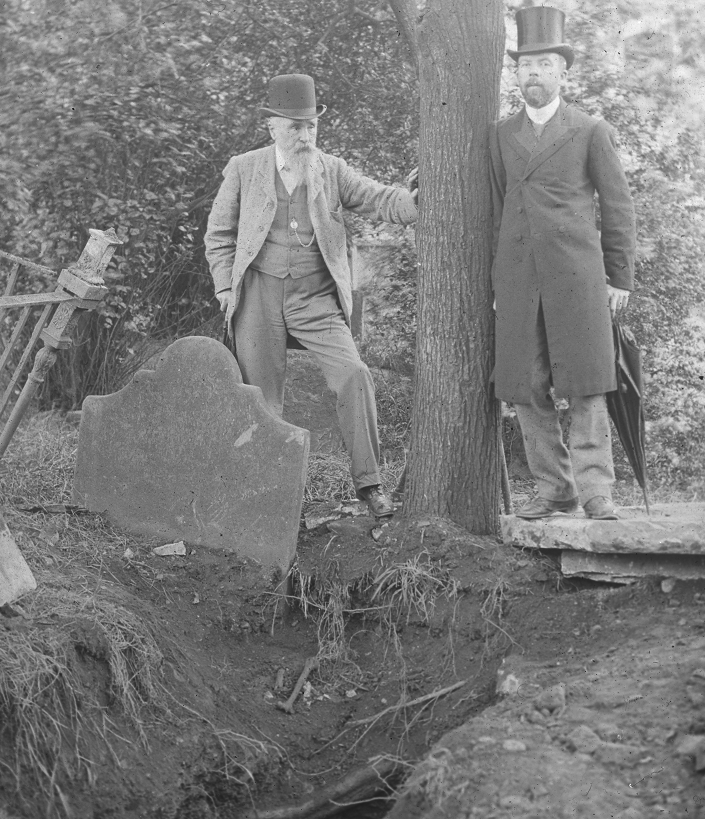 James Franklin Fuller and an unidentified person standing by a tree showing an excavated grave.