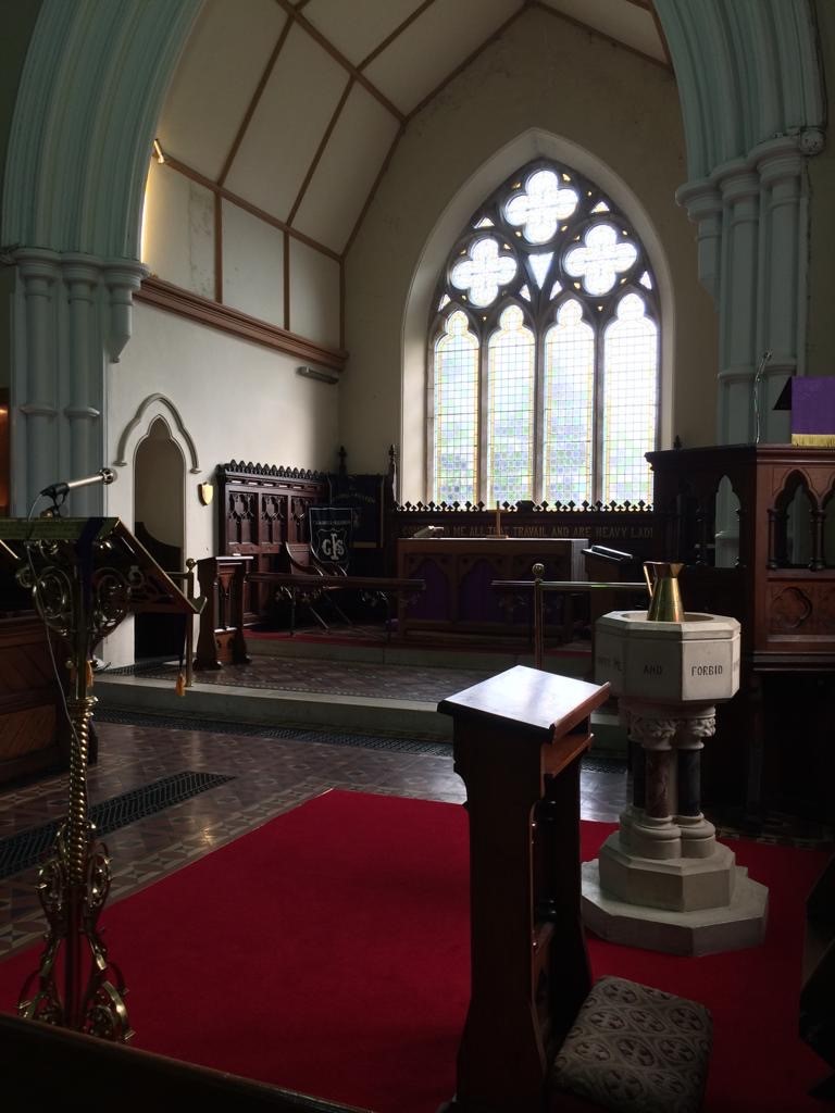 The interior of the church today, showing the east window, pulpit, extended chancel, wood panelling and the brass lectern.