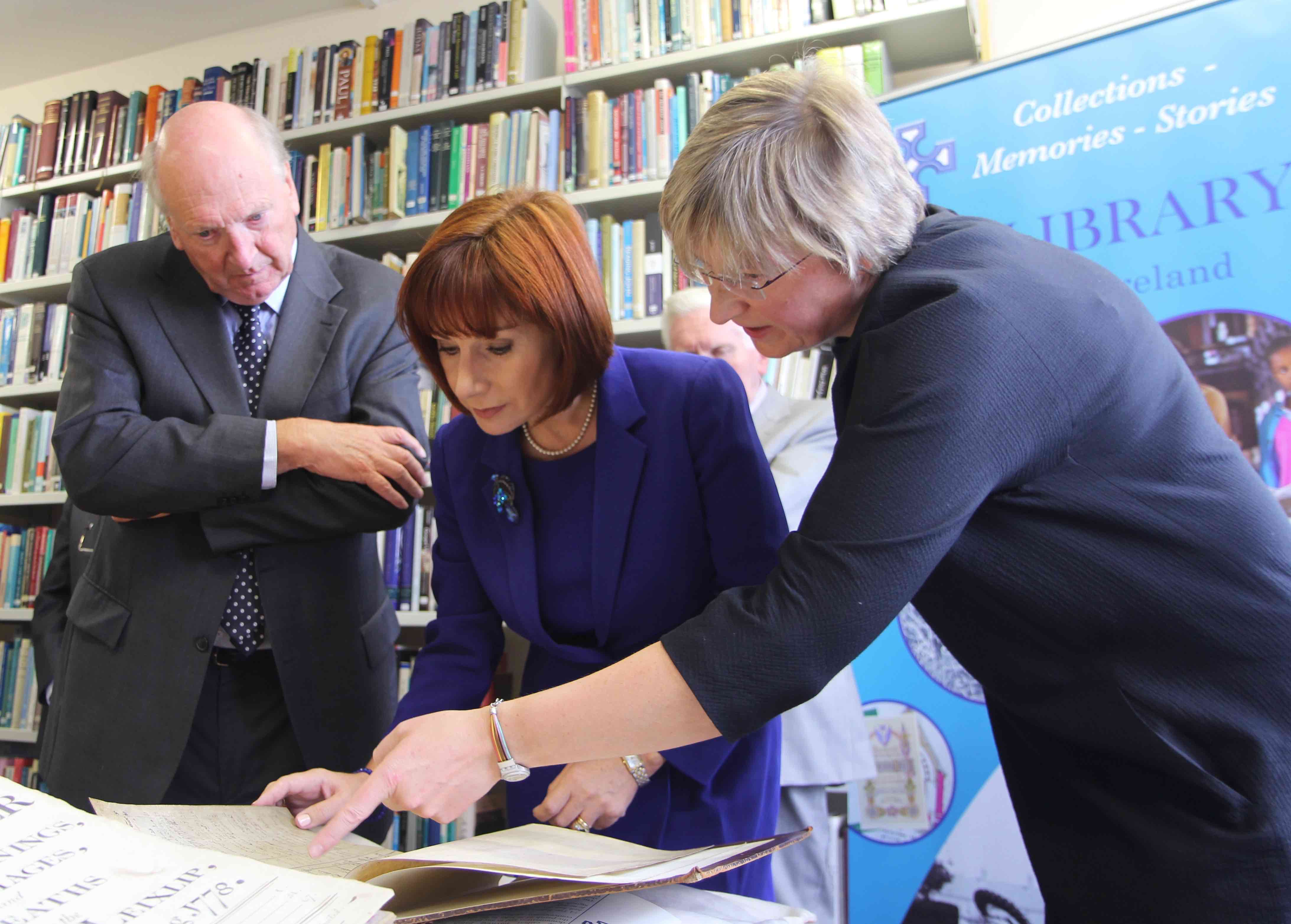 Minister for Culture, Heritage and the Gaeltacht Josepha Madigan TD viewing the register of St John's with the Librarian and Archivist, Dr Susan Hood, and Dr Michael Webb, Chairperson of the Library and Archives Committee.