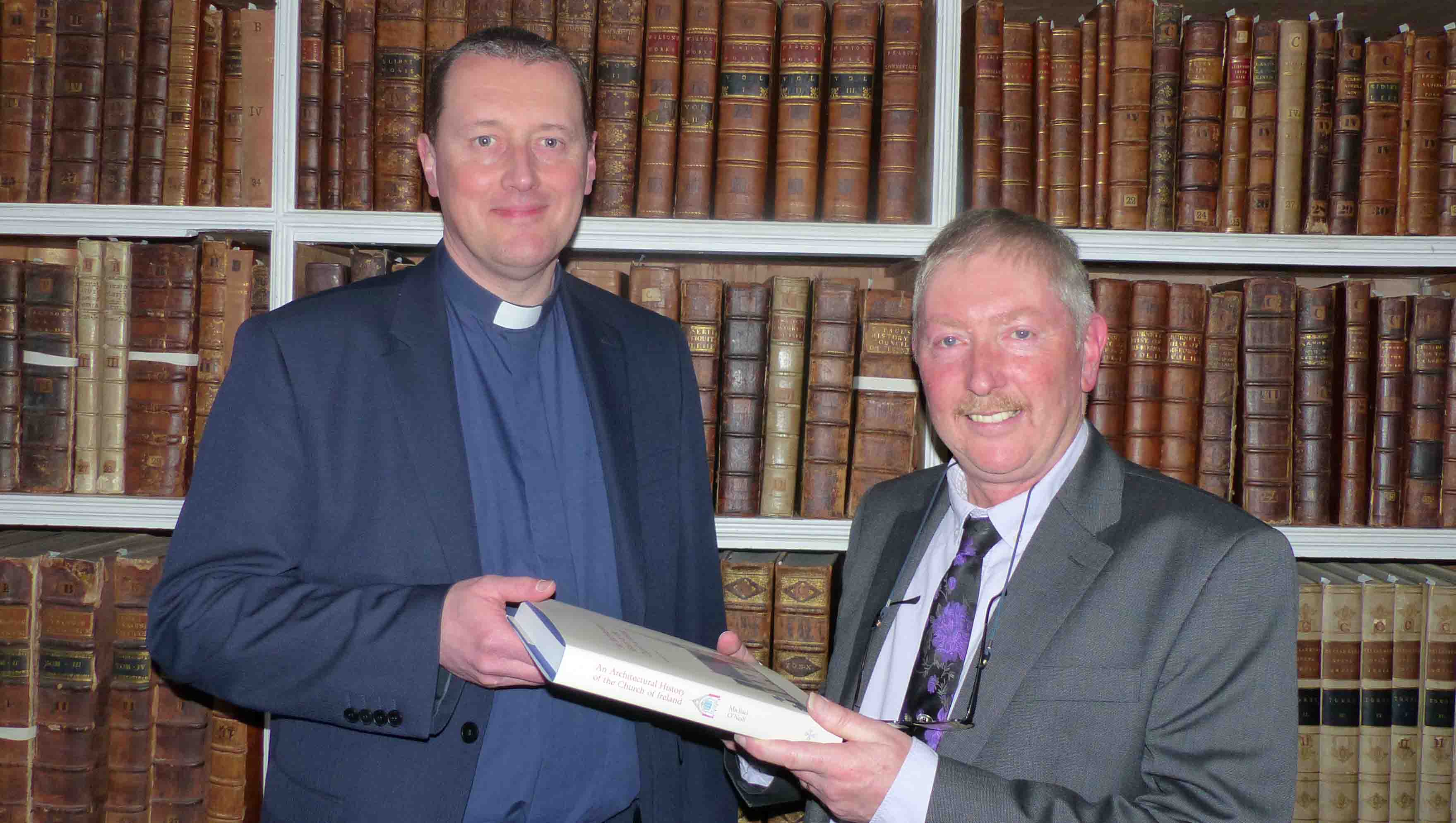 Dr Michael O'Neill presents the Very Revd Shane Forster with a copy of 'An Architectural History' for the Library's collection.