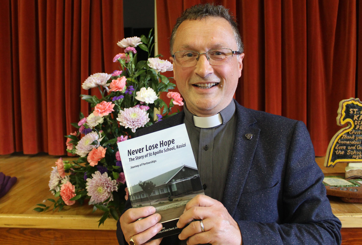 Archdeacon Paul Dundas with a copy of Never Lose Hope - the story of 'St Apollo School, Kasizi'.