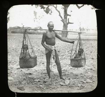 Man carrying two young children in balanced cane baskets